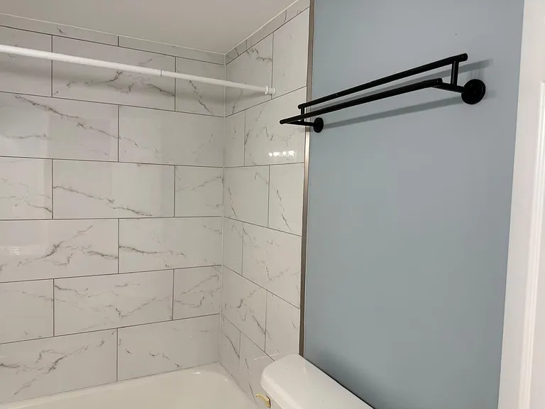 A very spacious bathroom with mother light factures and tiles.