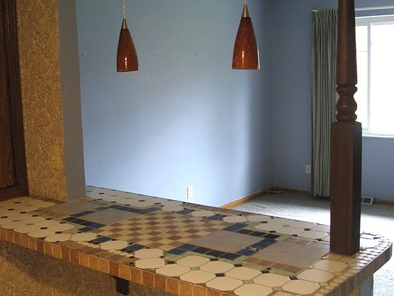 Breakfast bar with pendant lights and pantry to the left.
