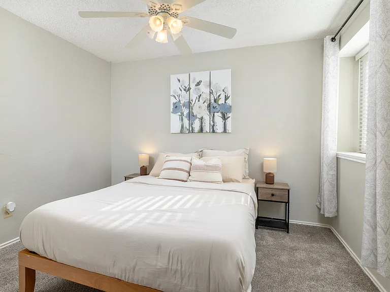 Upstairs Bedroom 3 features a queen bed, cozy carpeted floors, a ceiling fan, and plenty of natural light from the windows for a bright, inviting atmosphere.