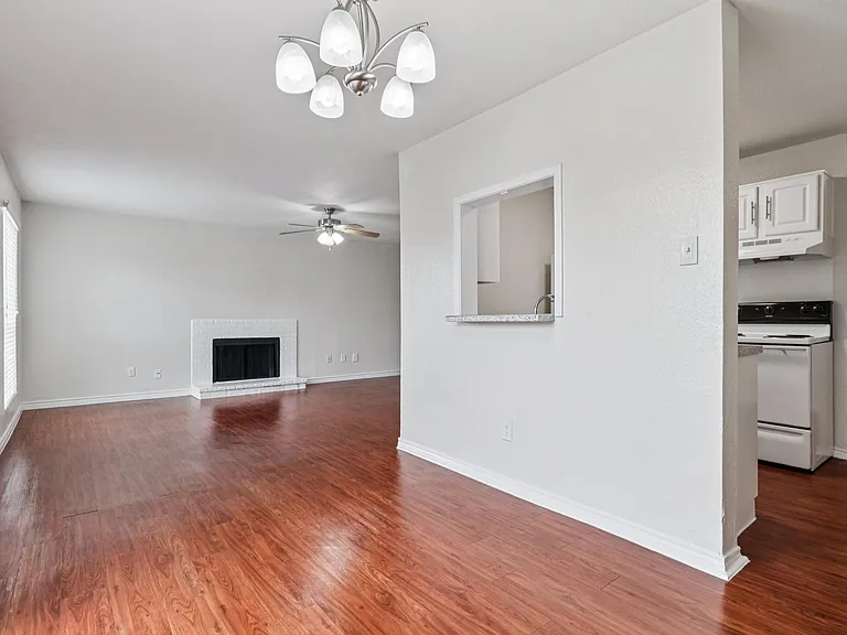Inviting open-concept living room with wood-style floors, a cozy white brick fireplace, and a modern chandelier, adjacent to a functional kitchen. Inviting open-concept living room with wood-style floors, a cozy white brick fireplace, and a modern chandel