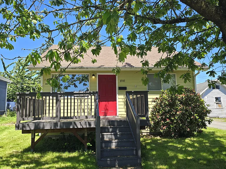 Front of home, shaded by leafy tree and set back slightly from street