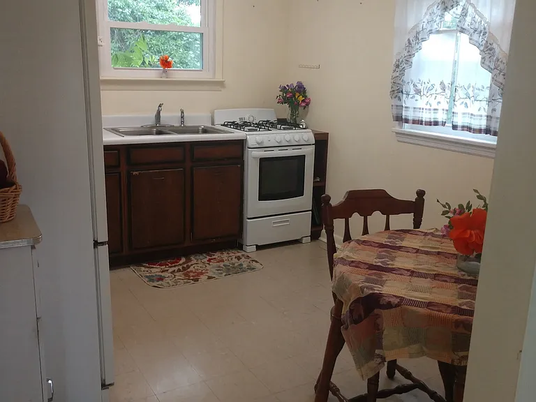 Bright eat in kitchen complete with: gas stove, full size refrigerator, microwave, sink, lots of cabinet space, table and chairs .