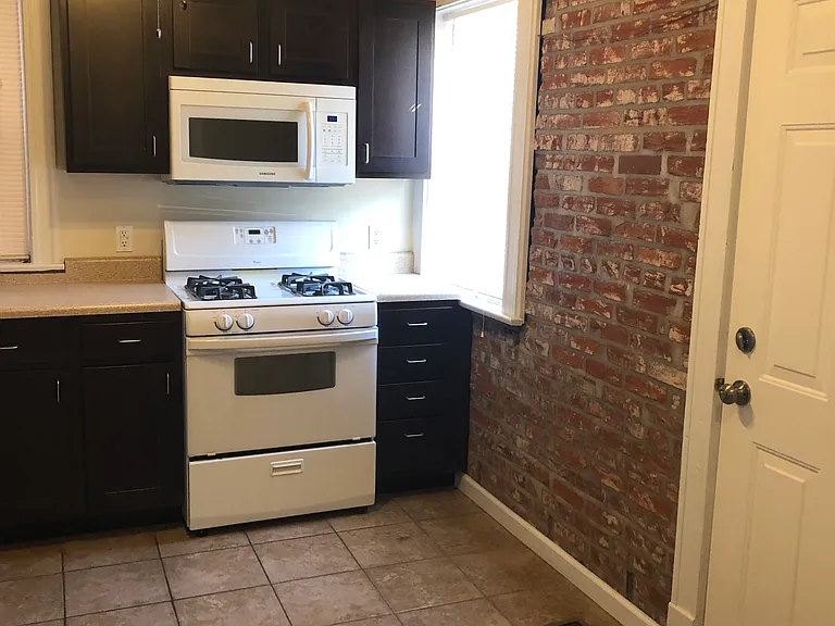 Kitchen with exposed brick wall, ceramic tile flooring, ceiling fan, and walks out to a private, covered deck.