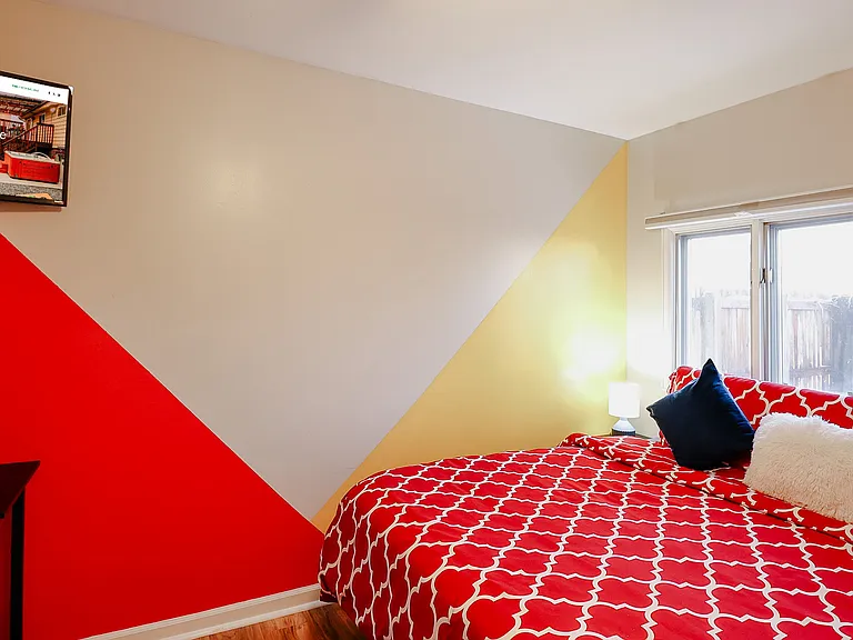 A bedroom painted with a cheerful palette of red, yellow, and white walls, creating a bright and inviting space that stimulates creativity and comfort.
