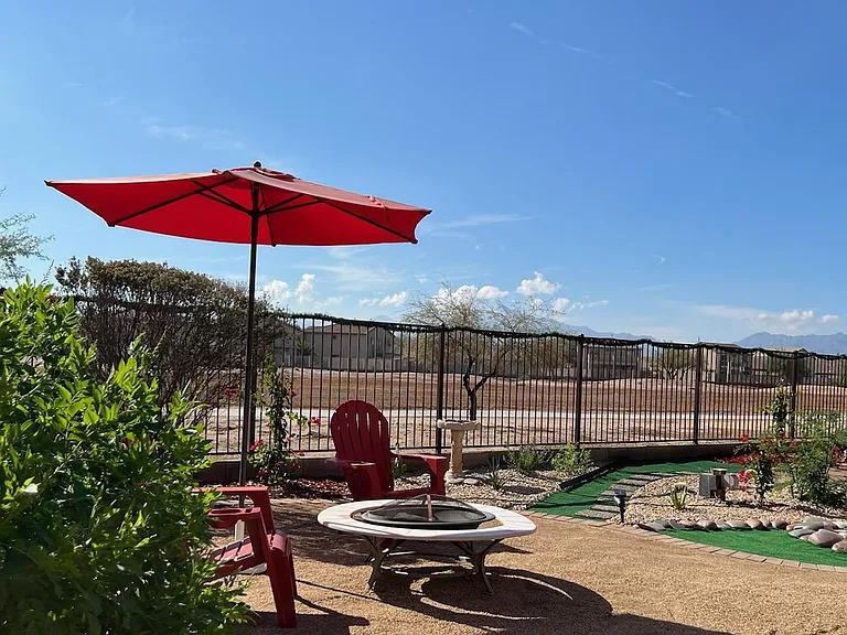 Beautifully landscaped backyard oasis featuring stunning Estrella Mountain and South Mountain views. Umbrella, chairs and firepit compliment the backyard space. Unwind and enjoy the backyard with family and friends! Picture taken November 17, 2023.