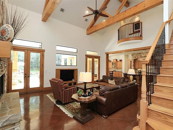 Family Room (from Foyer) showing off the Wood beams on ceiling, stone fireplace and French doors leading to pool area!
