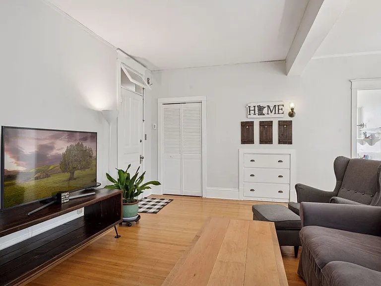 Second angle of living room, showing off main entrance, coat closet, and bonus entryway storage for seasonal items.