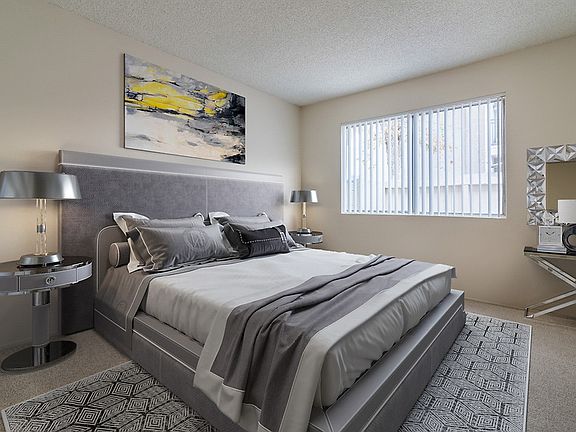Staged and carpeted bedroom with large window.