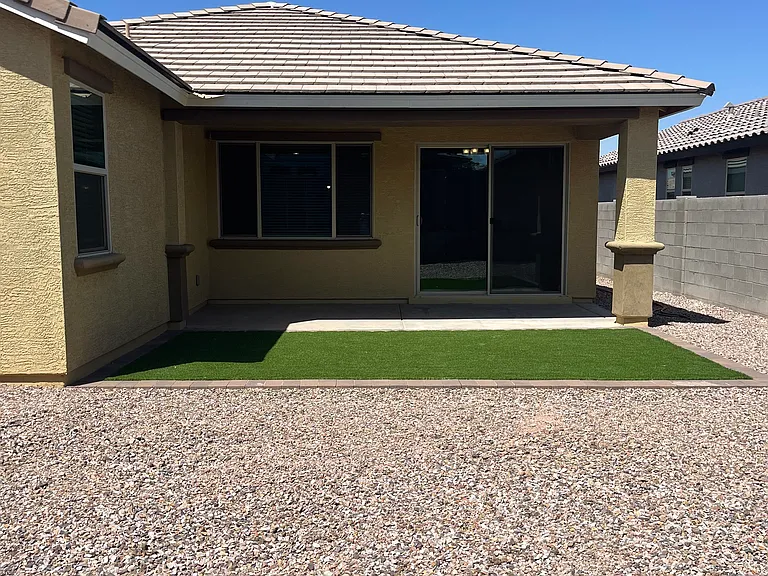 Covered patio in backyard with new turf, pavers and rock landscape. Patio shades living areas from afternoon sun.