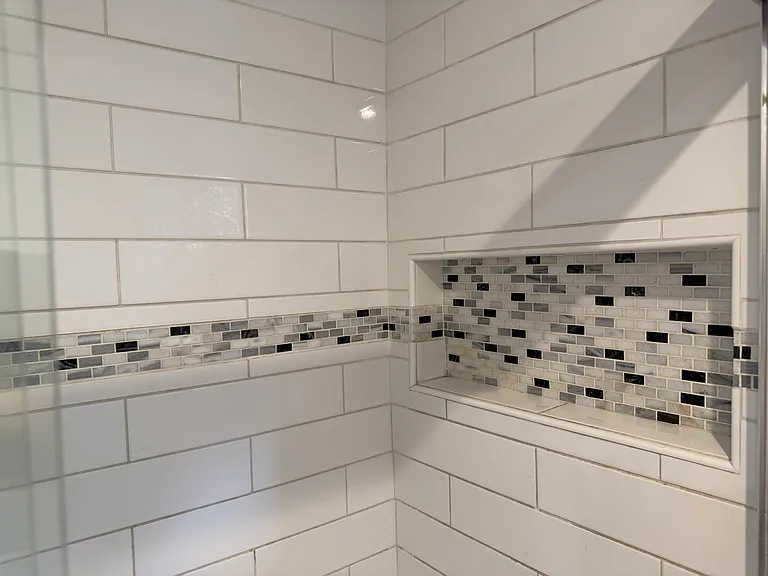 Custom tile shower with decorative accent tile and built-in niche.