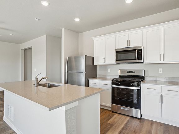 The kitchen has stainless steel appliances and white cabinets,