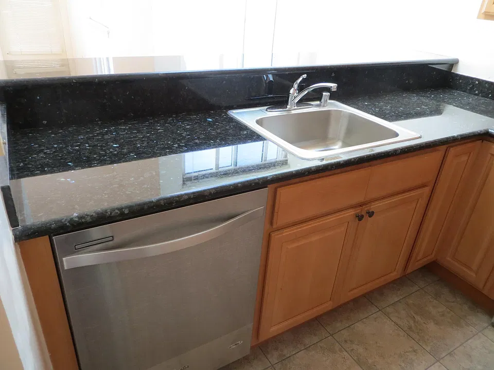 Stainless steel dishwasher, granite countertop, and sink