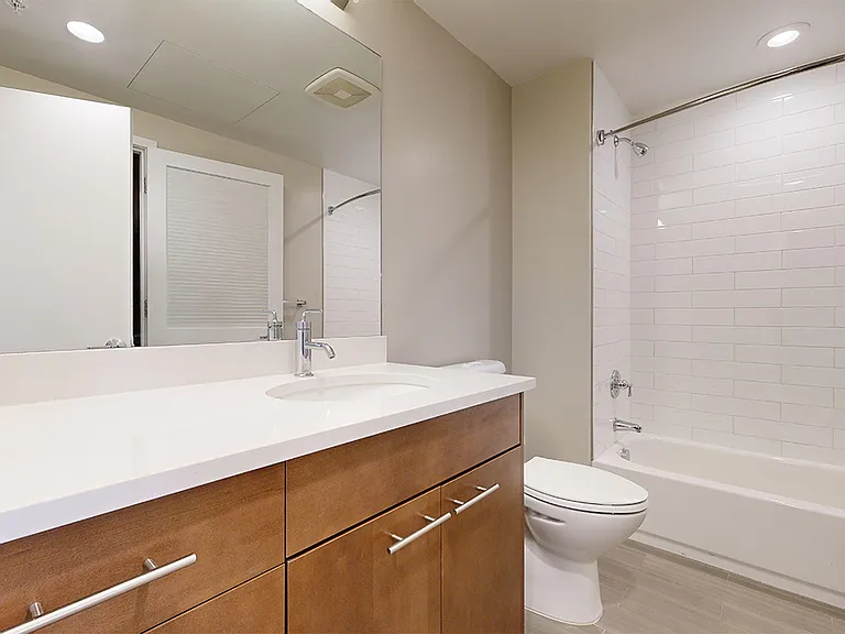 Apartment bathroom with wood-style flooring.