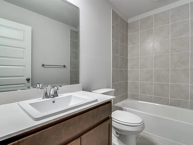 Bathroom featuring a single vanity with a white countertop and integrated sink, chrome faucet, and wood-finish cabinetry