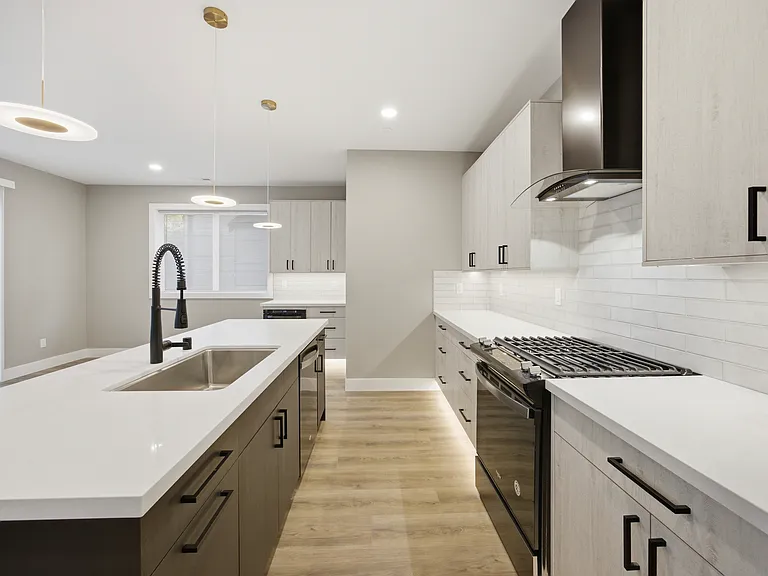 Large Quatz island, black hardware, Black chrome appliance finishes, commercial style faucet, dishwasher in the island, gas range.