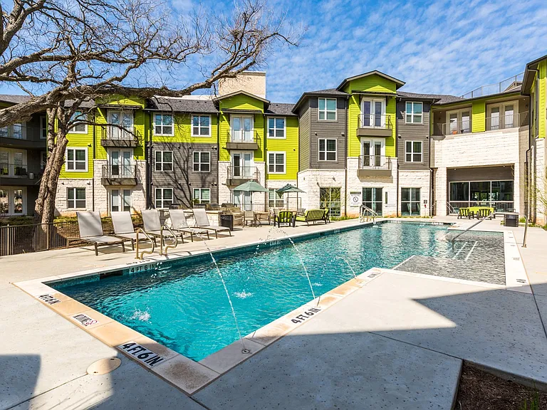 Pool with poolside lounge seating and umbrella shaded tables