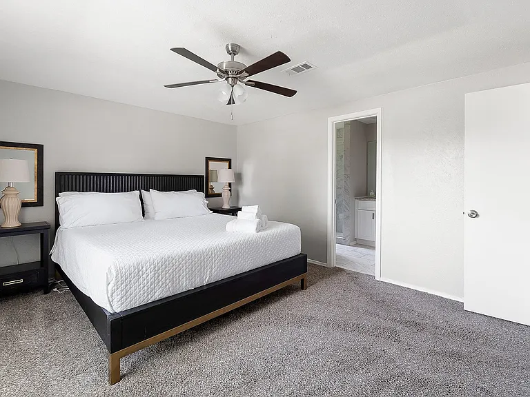 Primary bedroom with carpet flooring, ceiling fan, and connected bathroom