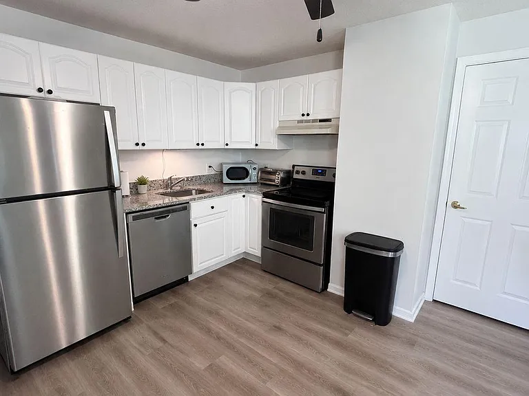 Functional U-shaped kitchen with ample white cabinetry, granite-look counters, and stainless steel appliances for easy meal p