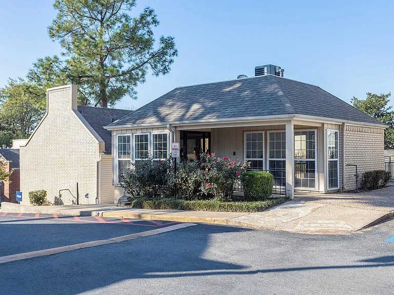 The exterior of the leasing office at ReNew on Cantrell is shown, framed by mature professional landscaping.