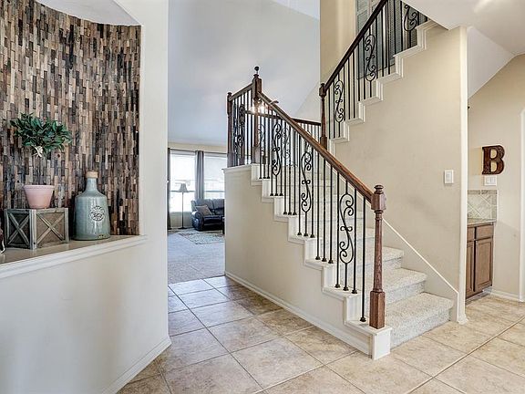 Large tile entry with art niche greets you upon entering. Staircase with wrought iron spindles and wood banisters lead you to second floor.