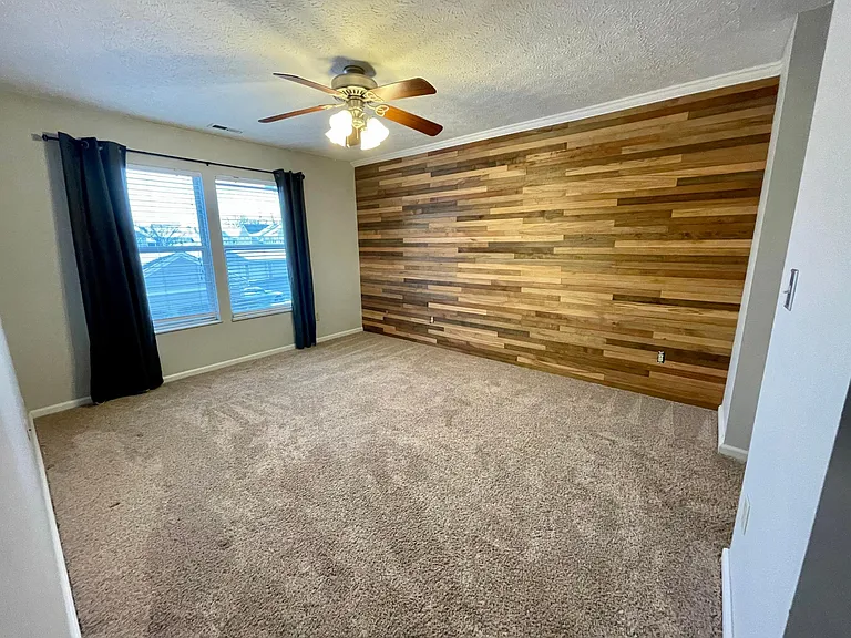 Spacious master bedroom with a gorgeous wood accent wall and ensuite bathroom.