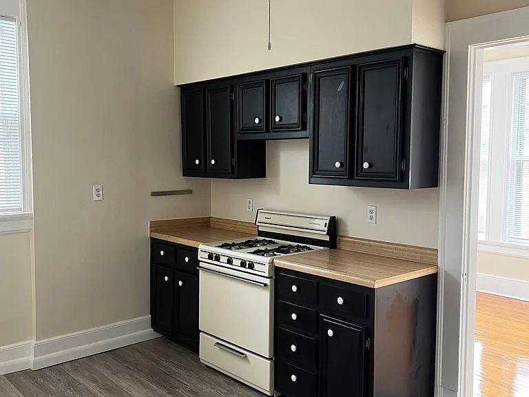 Kitchen view #1 shows cabinets, counter tops, stove, small table area and tiled floor.