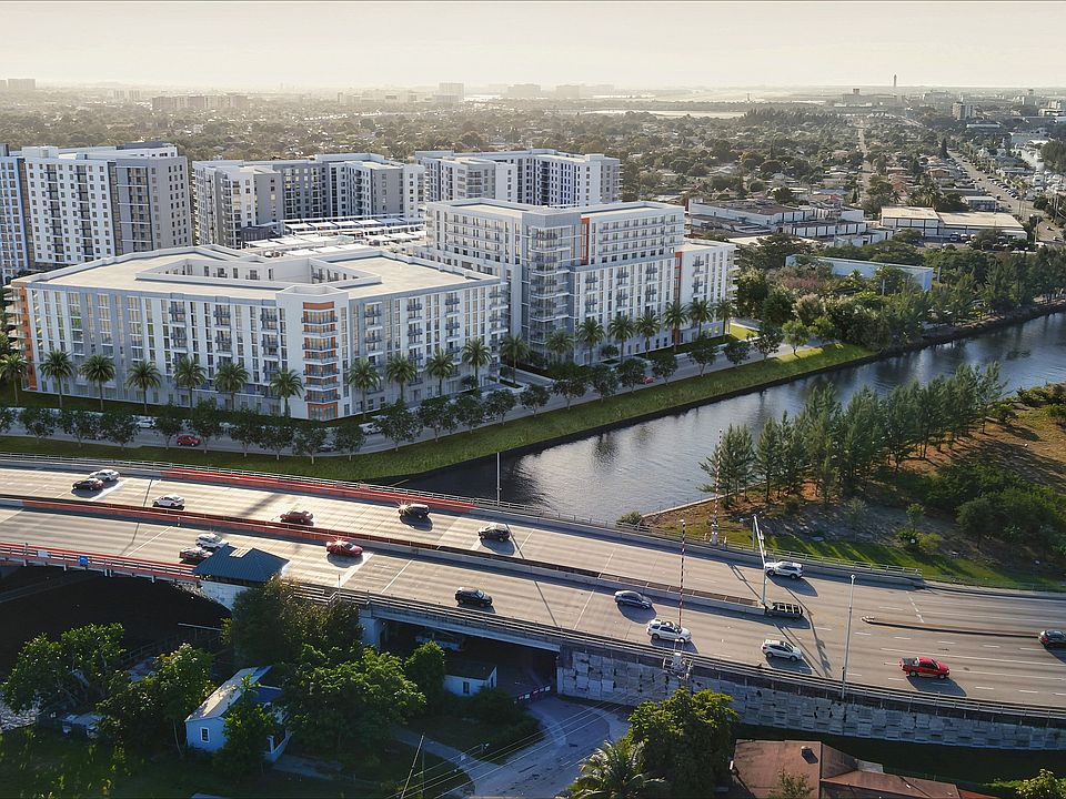 Elegant riverside apartment complex with modern architecture, lush greenery, and convenient location near a major highway, offering serene urban living.