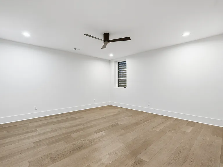 Spacious bedroom with modern finishes, recessed lighting, and a sleek ceiling fan.