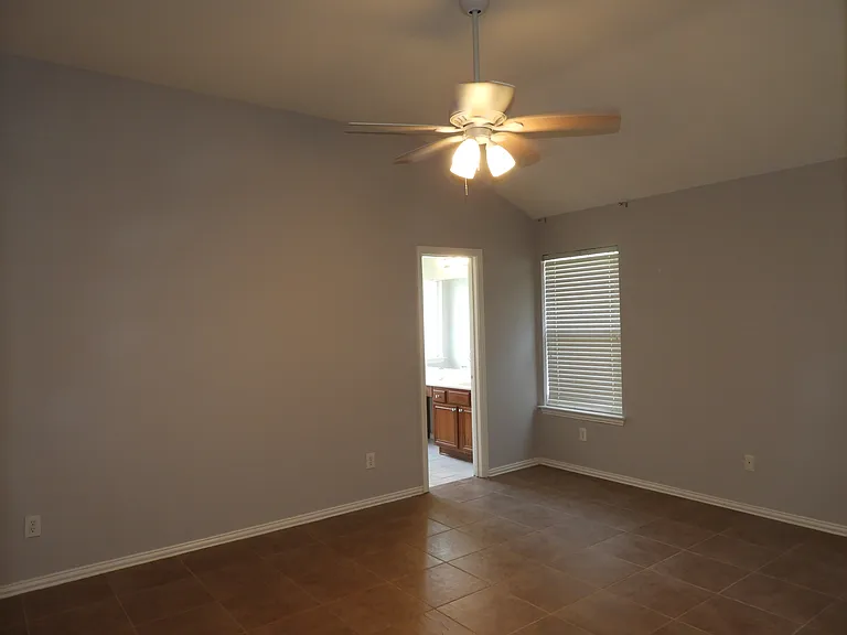 Oversized Primary bedroom. Tiled floors, ceiling fan and lots of natural light.