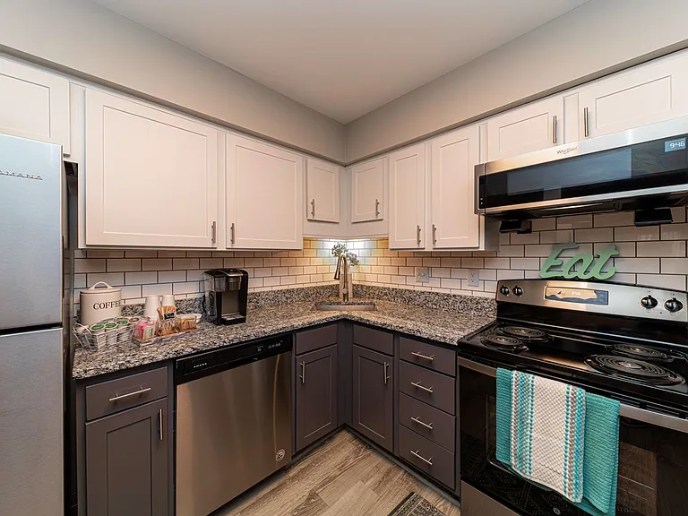 Kitchen with granite counters, stainless appliances, and two-tone modern cabinetry\