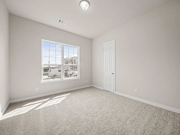 Bright and cozy third bedroom with plush carpet and sun-filled windows with a walk in closet.