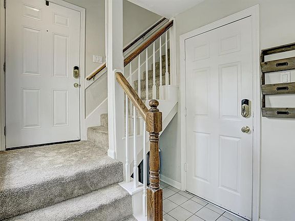 The off-white tiled mud room greets you as you enter from the front door or garage. Notice the extra storage place under the stairs.