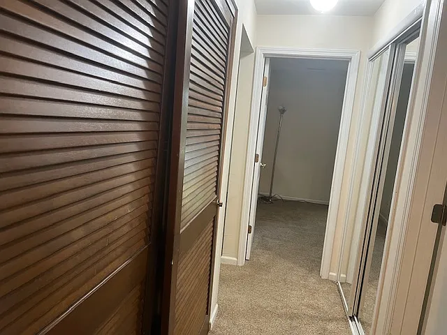 view into second bedroom with utility room on the left and large mirrored closet on the right.