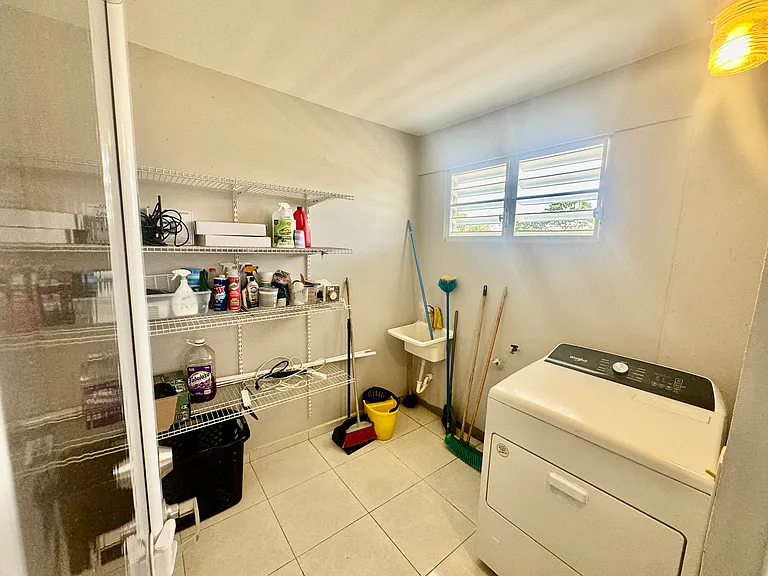 Spacious laundry room dived with door next to designated office space with shelves, includes an electric clothes dryer and connections for a washer.
