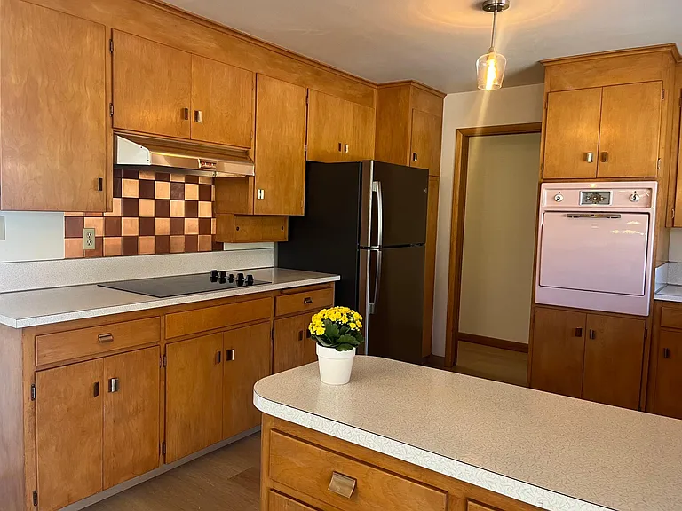Kitchen with new stainless fridge and vintage pink oven. New flooring.