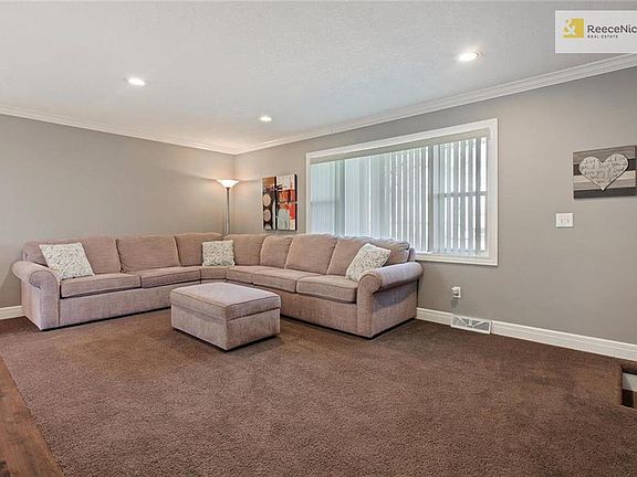 Large main-level living room with nice carpet and picture window. Crown moulding and recessed lighting update the space.