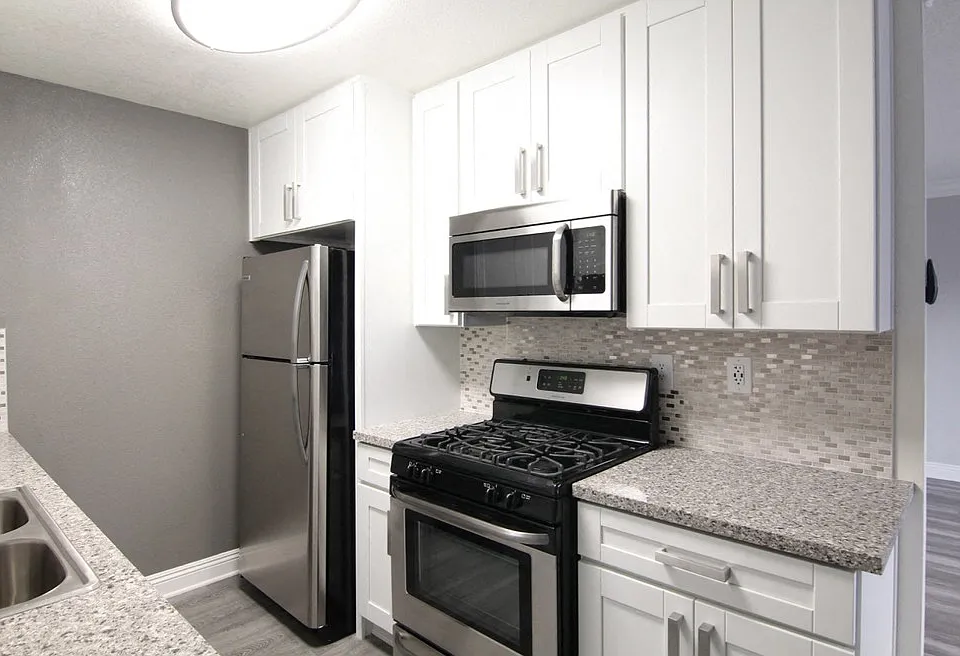 Kitchen with quartz stone counters and stainless steel microwave, oven, fridge, and fixtures.