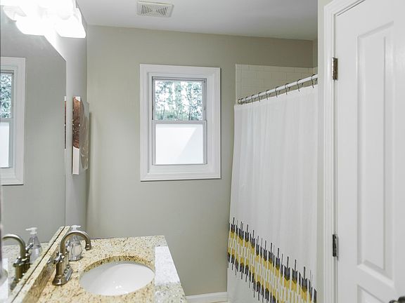 Hall full bath with stacked laundry in closet for convenience.