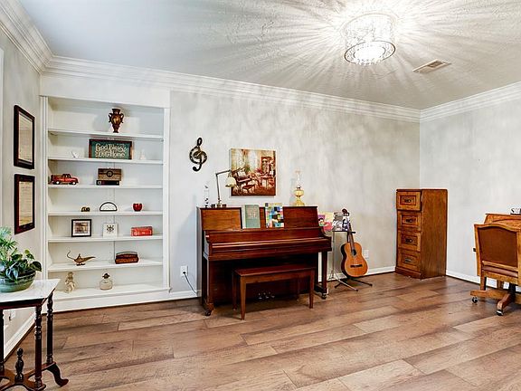 Spacious office with French doors, built in shelves, wood floor and plantation shutters.