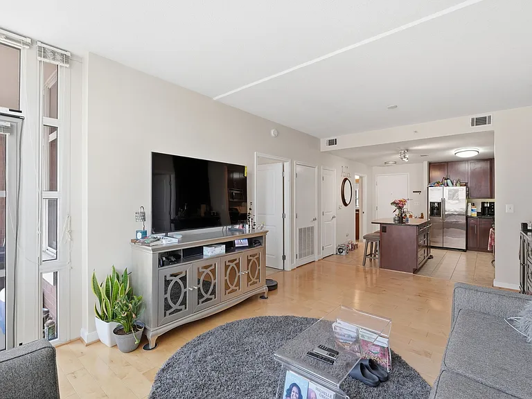 Open-concept living room with hardwood floors, abundant natural light, and access to the balcony.