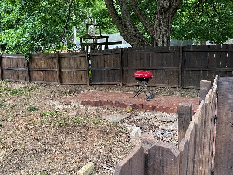 Fenced side yard w brick patio and grill