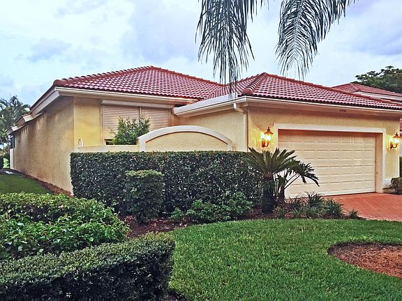 The front of the home, from Quail Village Way. On the left is an open atrium off of the Master Bedroom, with a storm shutter that is shown mostly closed, but that can be fully opened. The two car garage has added space for a golf cart (or extra storage).