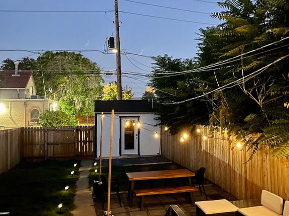 Large, grassy backyard complete with large outdoor couch and acacia wood outdoor dining table.