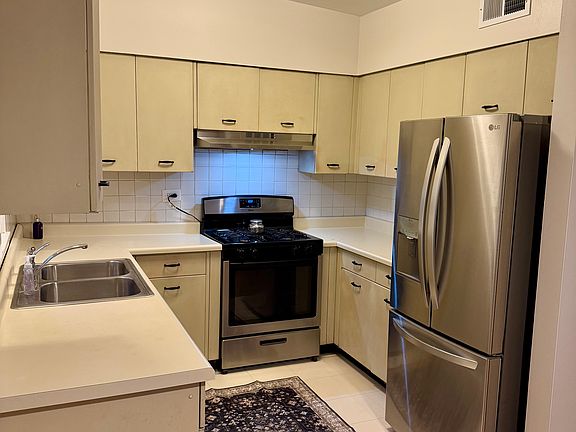 Charming retro-style kitchen with brand new French door refrigerator, new stove hood, stainless steel appliances, and plenty of natural light.