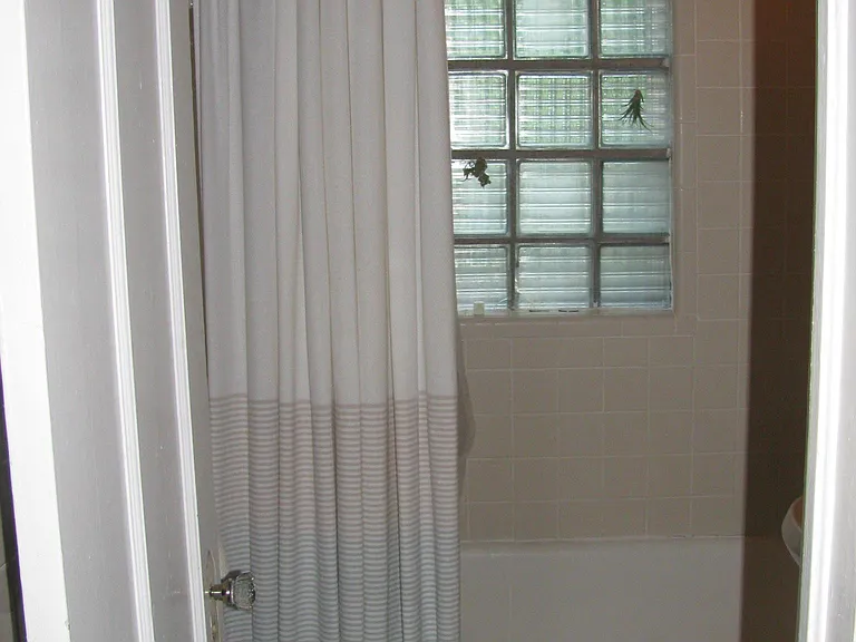 Tiled bath with combo tub/shower and glass block window.