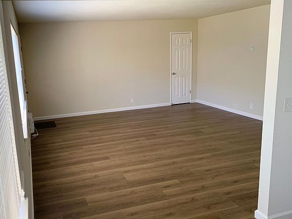 View from the kitchen into the living room showcasing the new vinyl plank floors. The door pictured leads to a spacious 20 sq ft bonus storage closet.