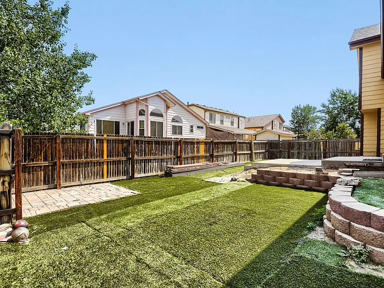 Backyard with artificial grass, concrete patio and sitting/bbq area with pavers