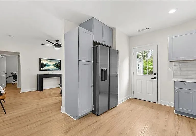 Open-concept kitchen area with ample cabinetry, stainless side-by-side fridge, and convenient exterior door access.