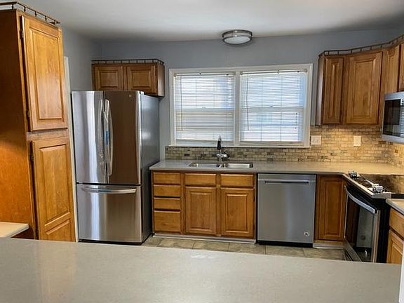 Kitchen ( 11'8" x 11') with stainless steel appliances (brand new French door refrigerator, smoothtop range with convection oven, and OTR microwave and newer dishwasher), quartz countertops, slate backsplash, porcelain tiled floor