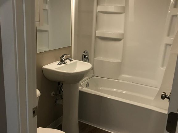 Pristine bathroom includes a large tub and a medicine cabinet for extra storage.